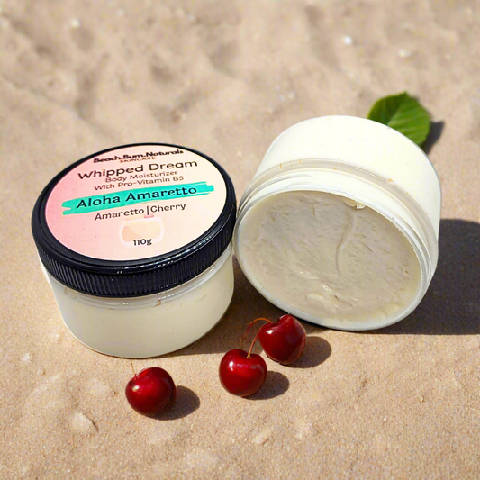 Whipped Dream body moisturizer jar with a pink label on a sandy background with cherries