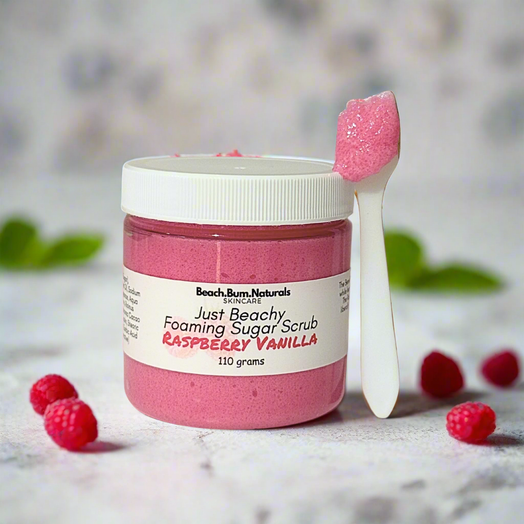 Pink foaming sugar scrub with a spoonful of scrub on a white background