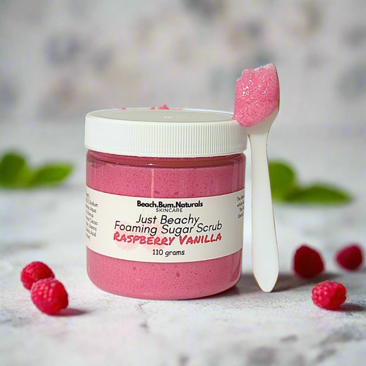 Pink foaming sugar scrub with a spoonful of scrub on a white background